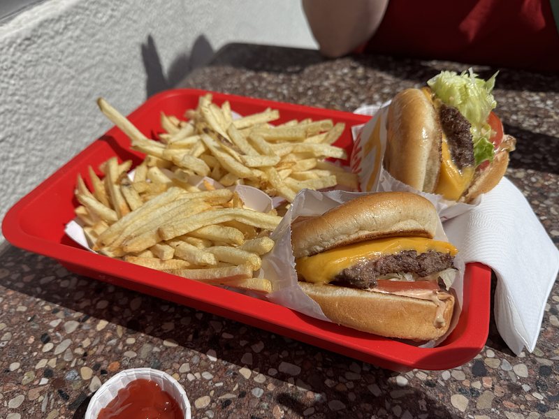 red plastic tray holding two cheeseburgers and two orders of French fries