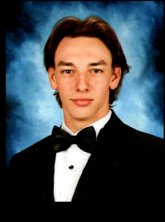 Senior portrait of my nephew Maxwell in a black tuxedo and bow tie, looking confident against a classic blue background
