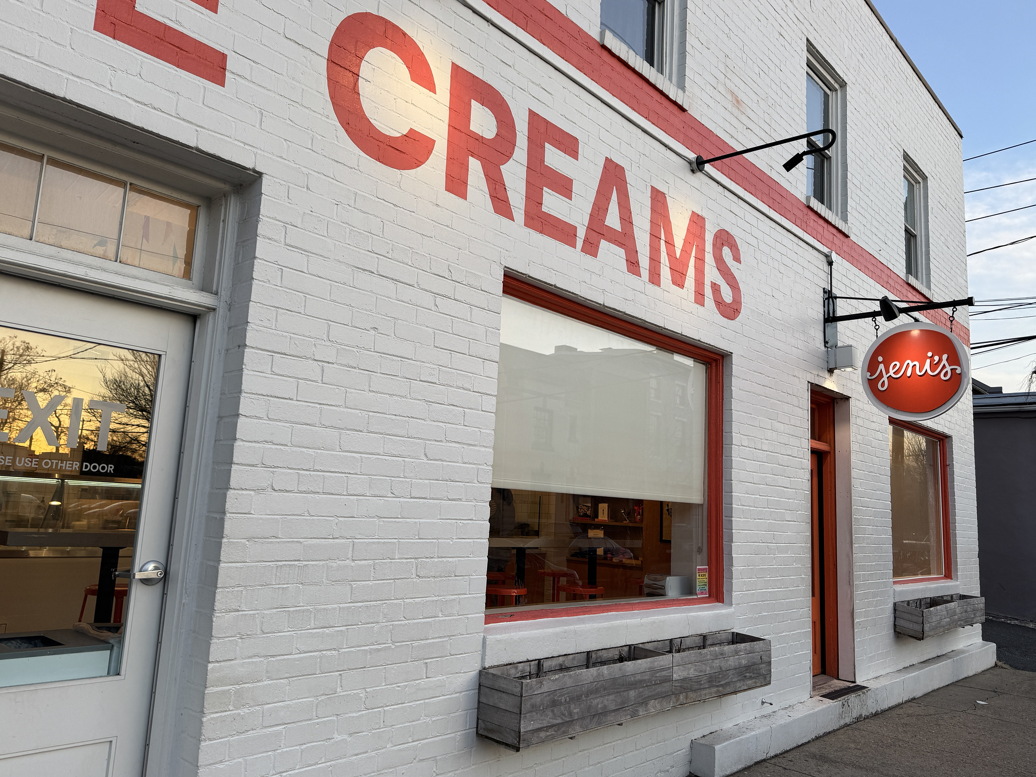 white brick storefront with orange brick trim. painted "creams" on the front and a hanging sign that reads "jeni's"