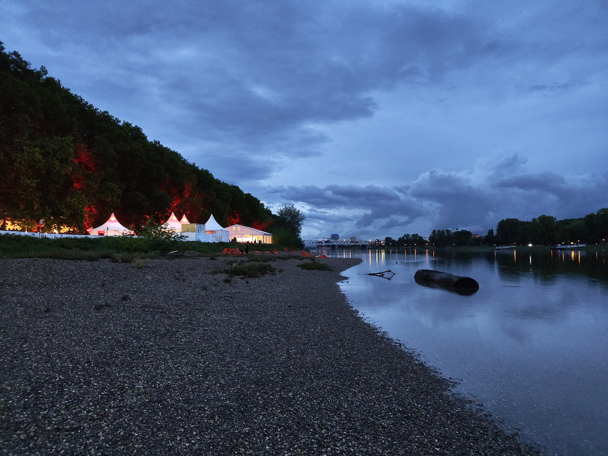 A dark evening sky above the Rhein river and the lighted tents of the German Film Festival