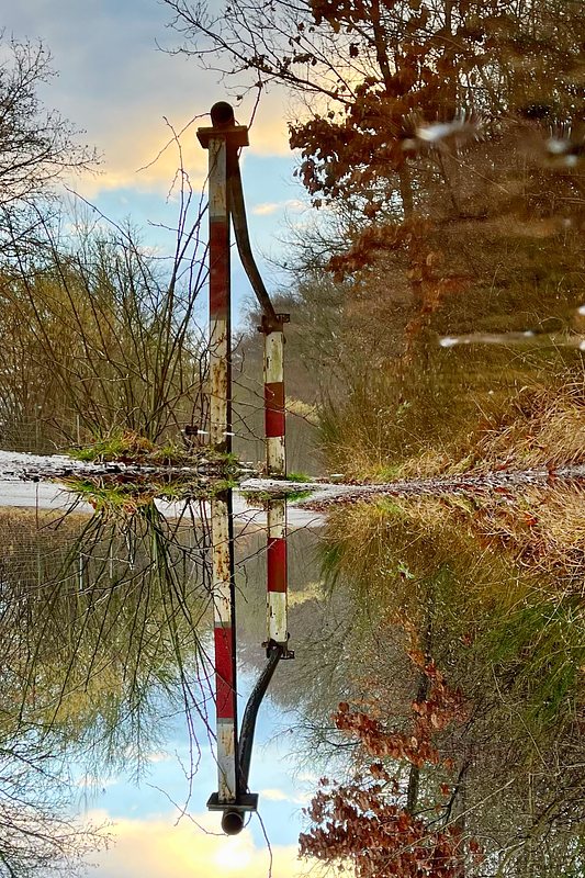 Reflected Image of a Barrier Gate in puddle, turned upside down.