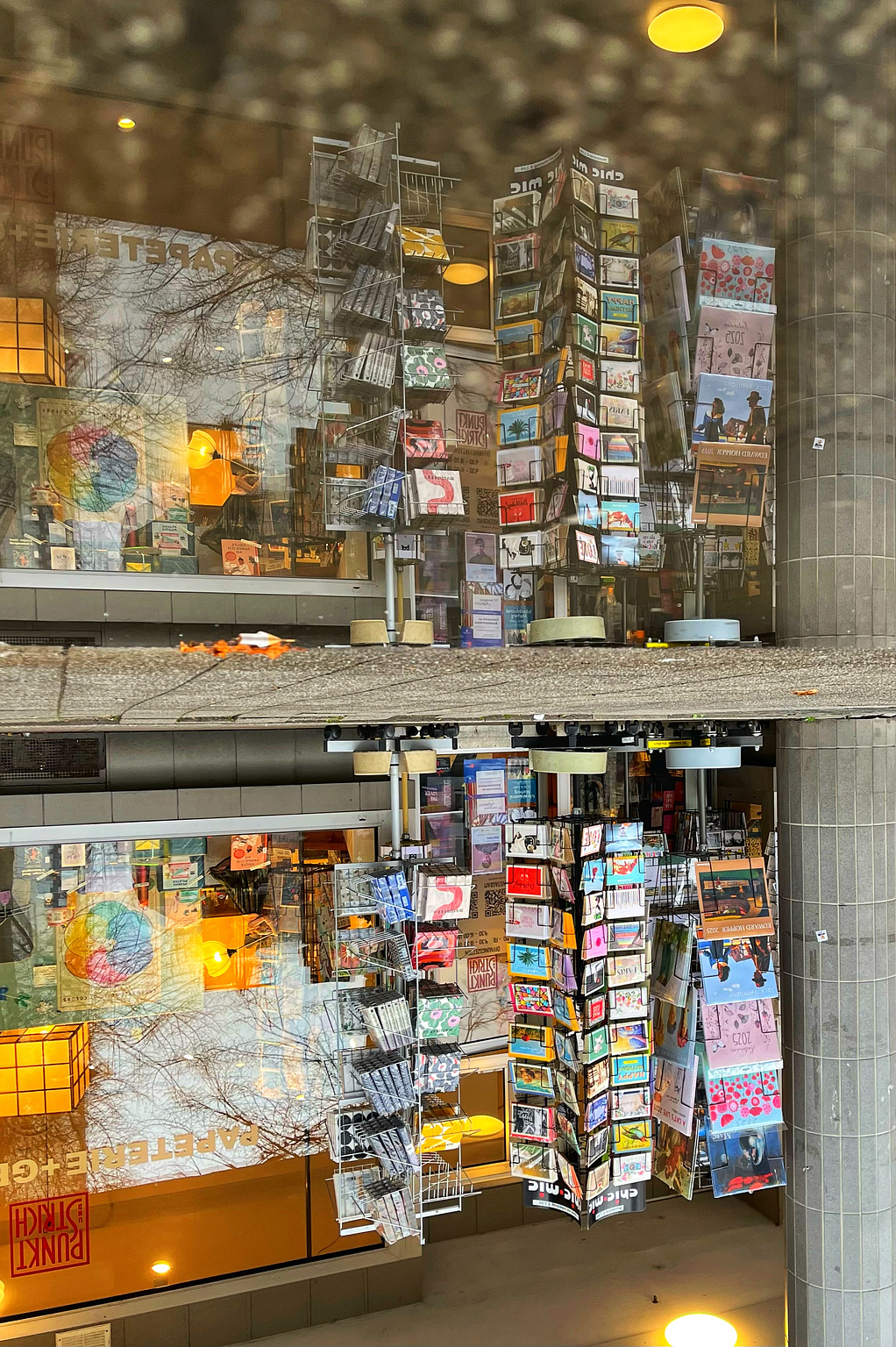 Schaufenster eines Geschenkeladens spiegelt sich in Pfütze.