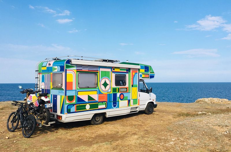 Colourful campervan parked with a view towards the ocean