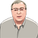 Digital illustration of a middle-aged man with glasses, short light hair, and a light gray button-up shirt, shown from the shoulders up against a transparent background.