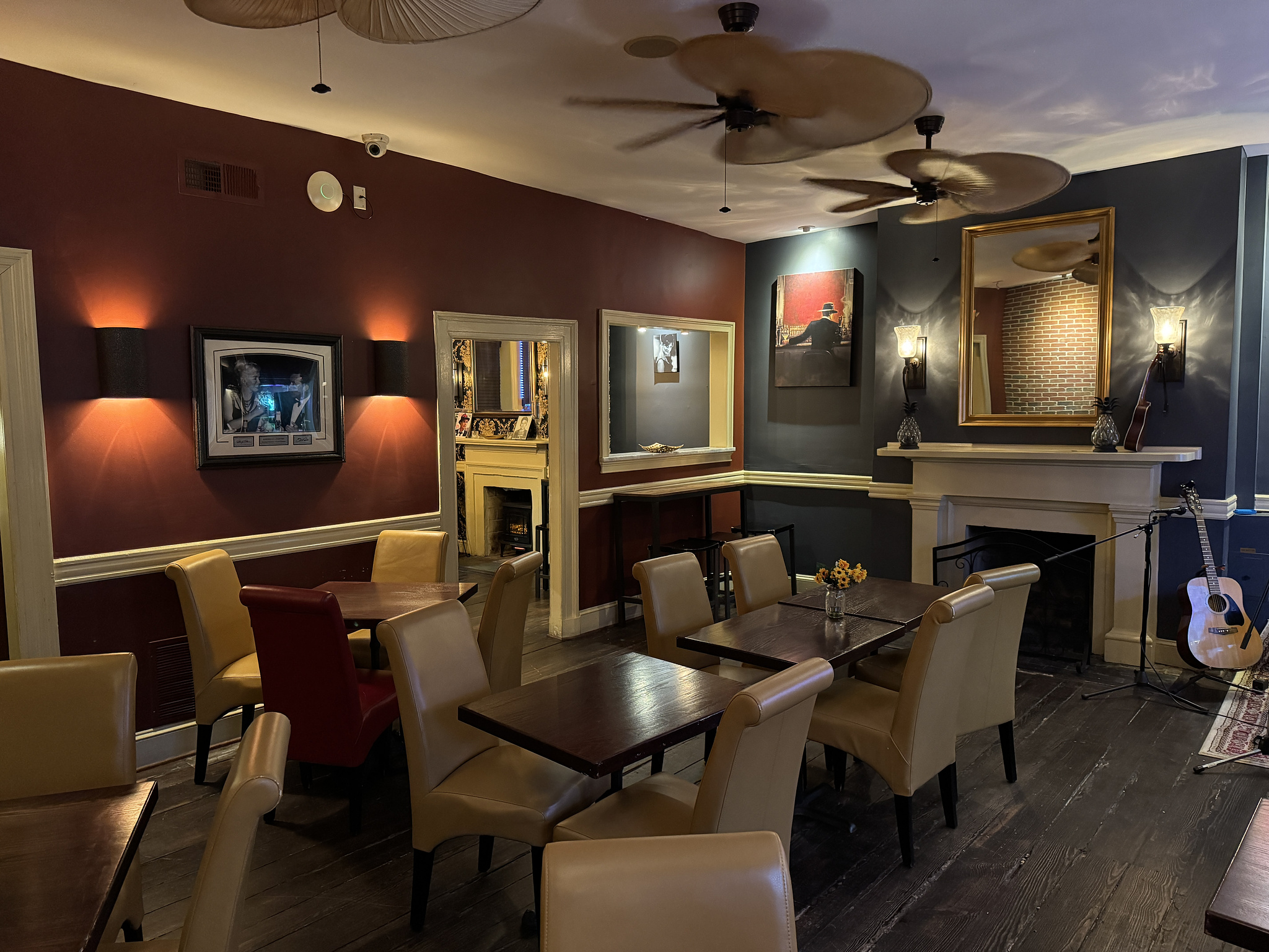 restaurant room with several tables and chairs setup, a fireplace on the far wall, and a guitar leaning against the wall in the corner