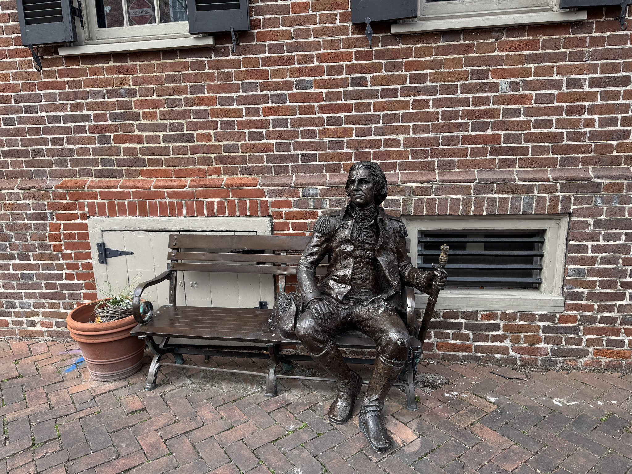 bronze statue of a revolutionary soldier sitting on a bench. 