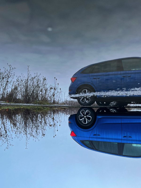 Reflection of a blue car in a puddle.
