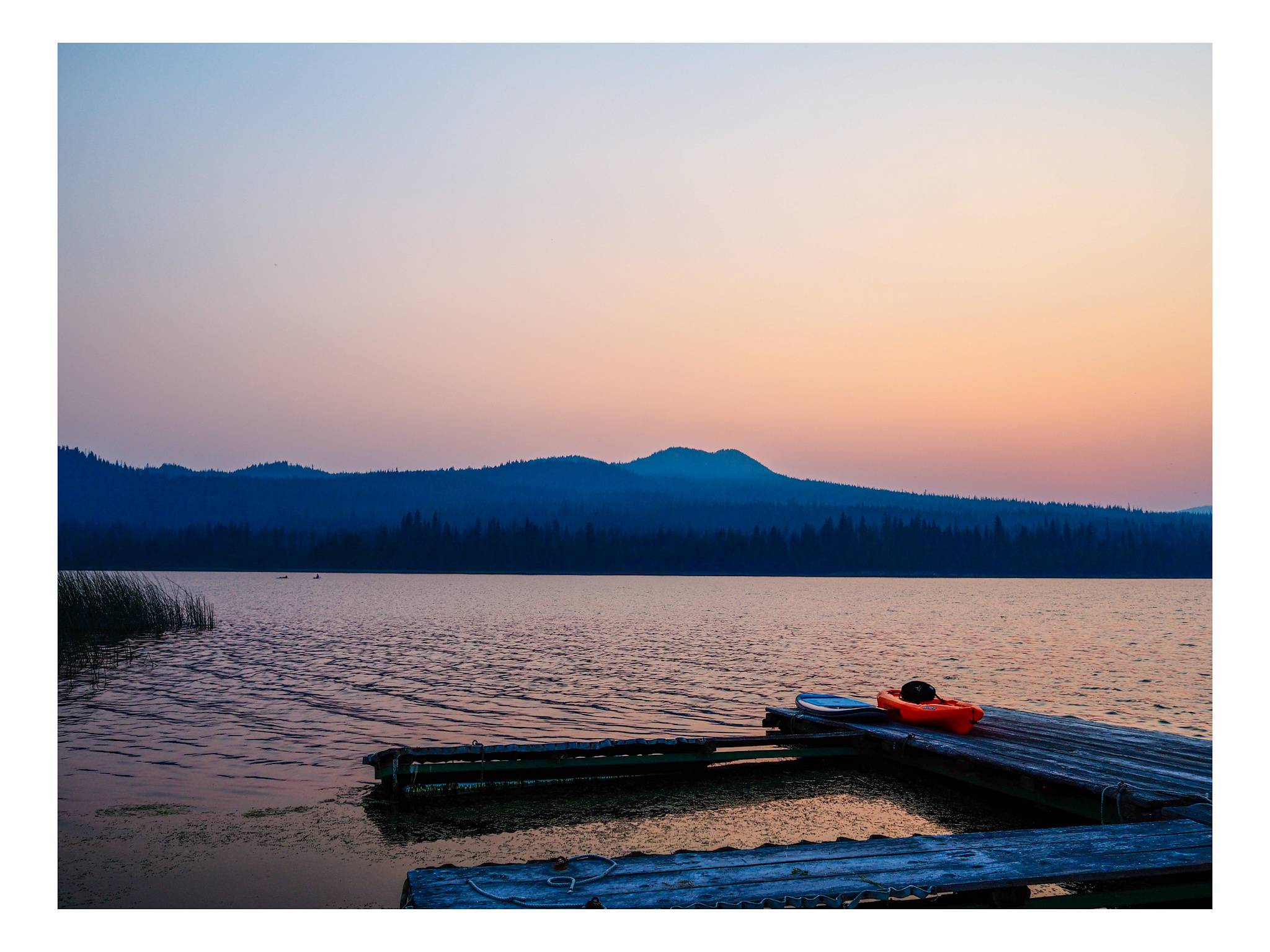 Orange kayak on a dock under a Hazy, muted  sunset over a Central Oregon lake