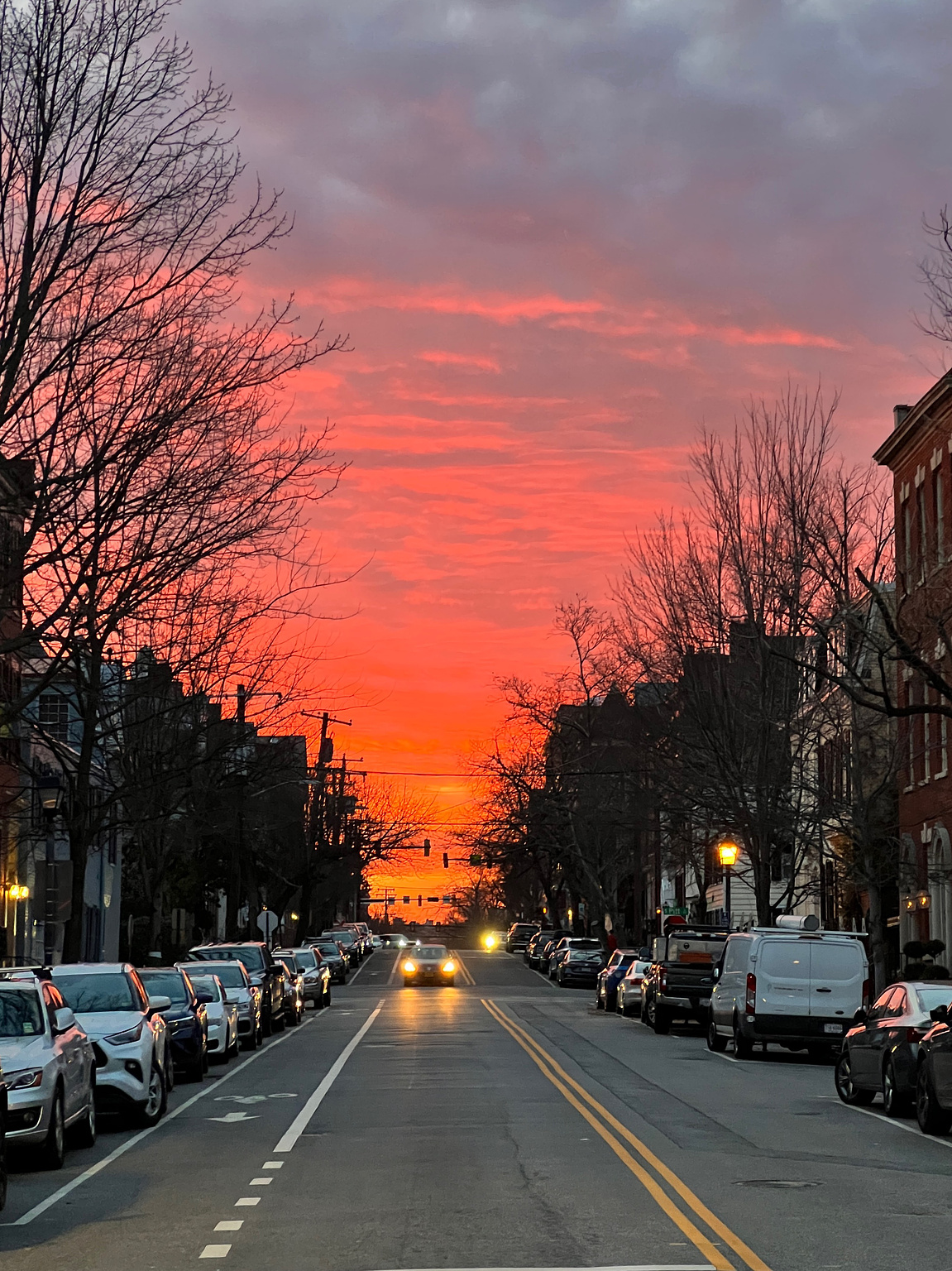 sunset in the background while looking down a city street