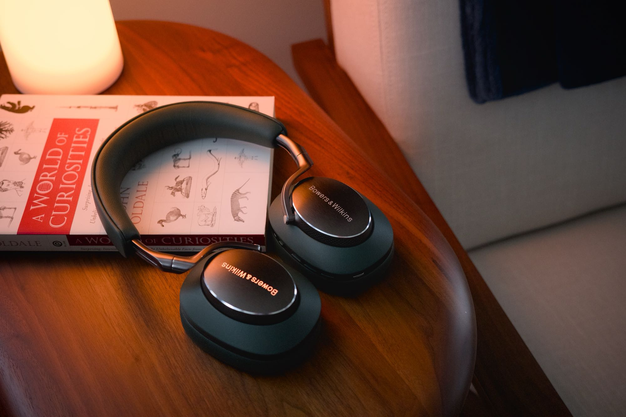 Bowers & Wilkins Px8 headphones in forest green on a walnut side table, resting on a book.