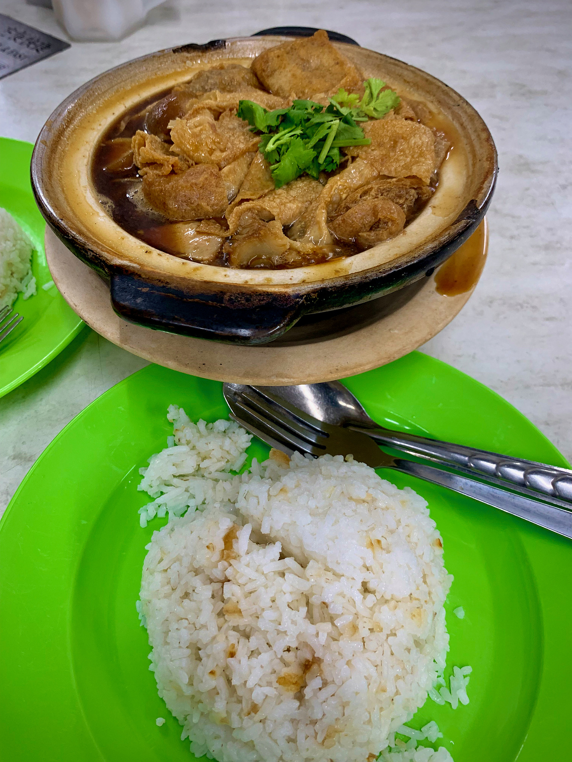 A bowl of local pork soup with a cup of cooke rice.