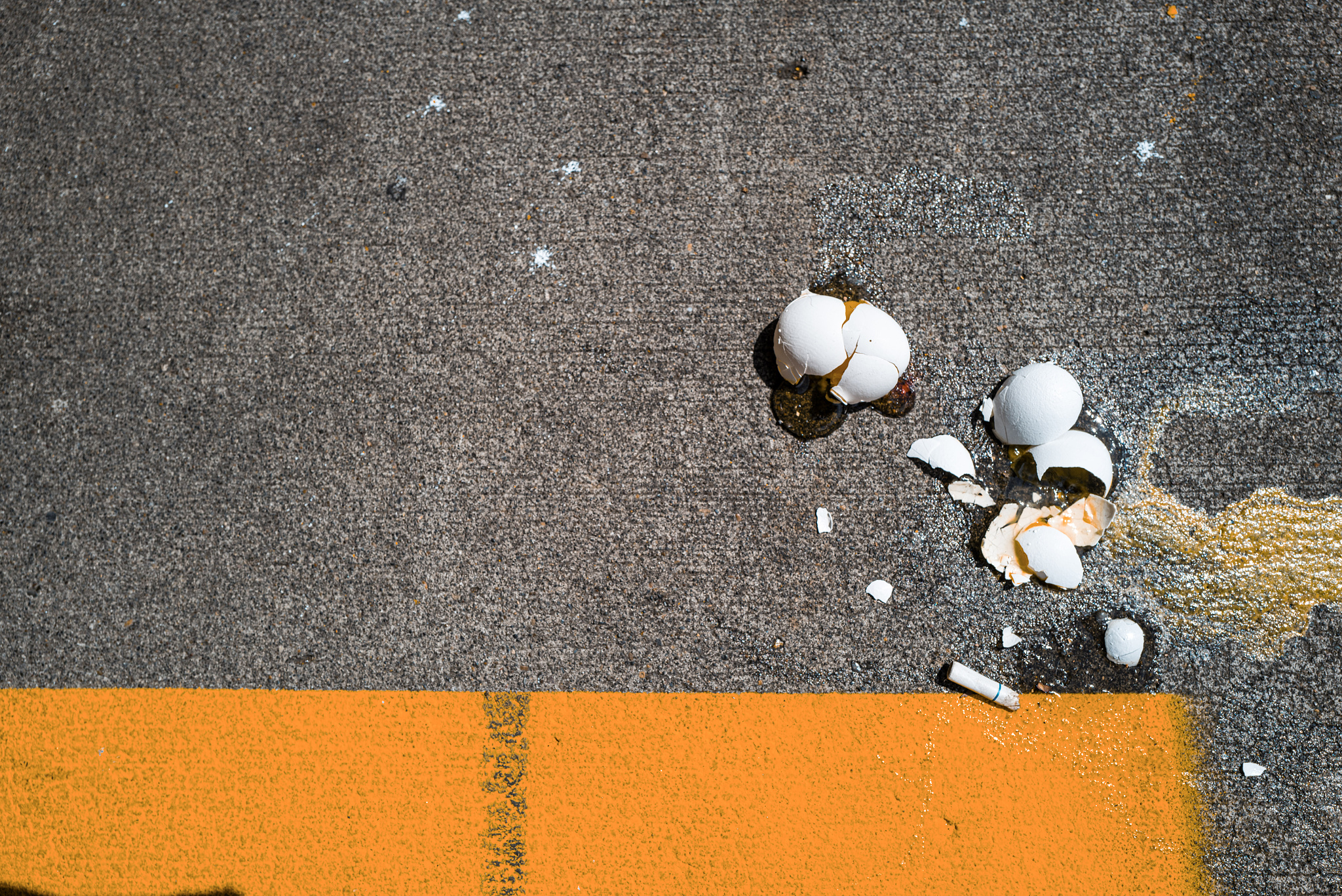 Broken eggs and cigarette butts on concrete