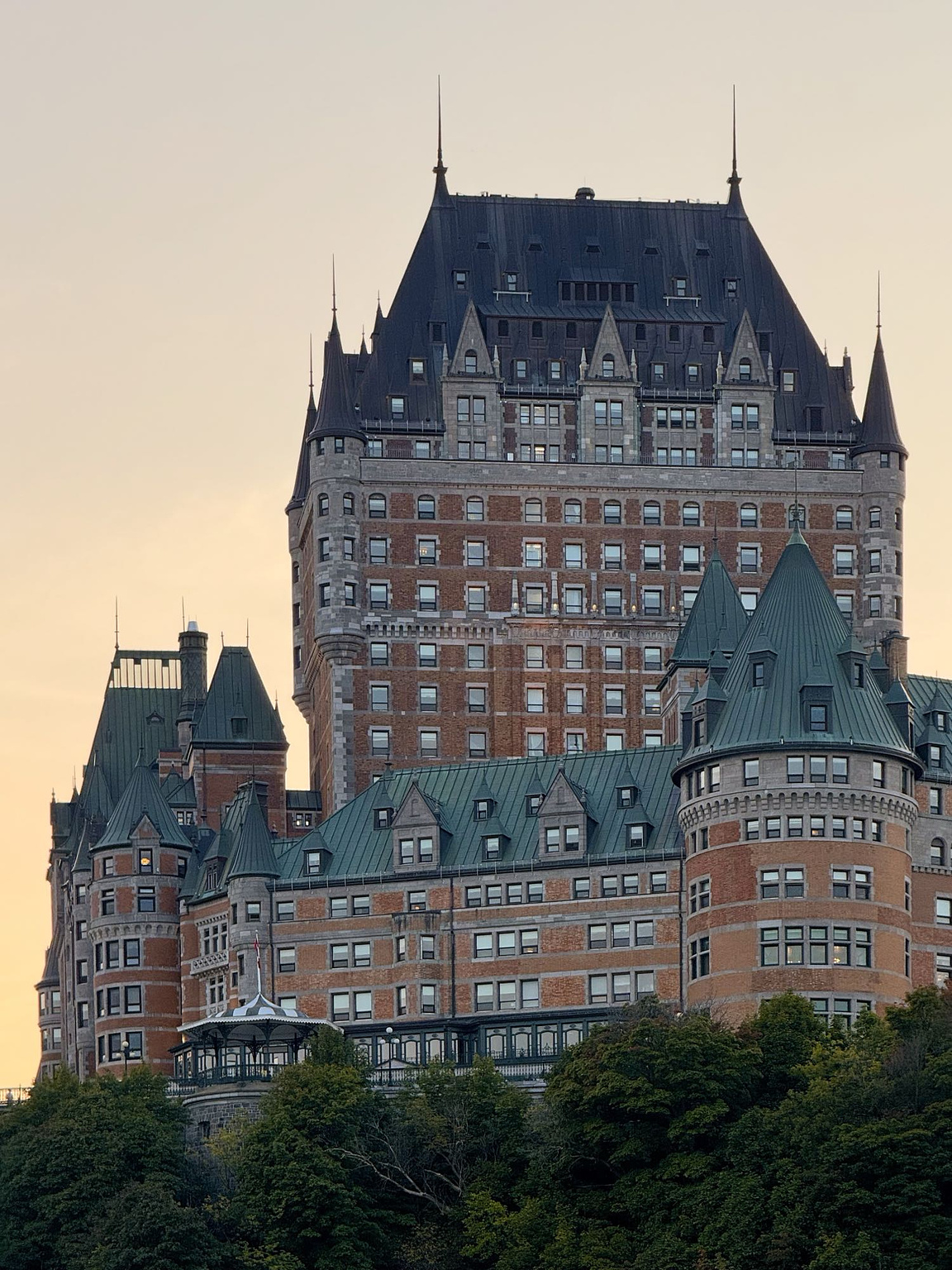 Fairmont Le Château Frontenac, the magnificent-looking castle that looms over Quebec City, Canada. This telephoto perspective casts the central towers of the castle against a glowing sunset sky.