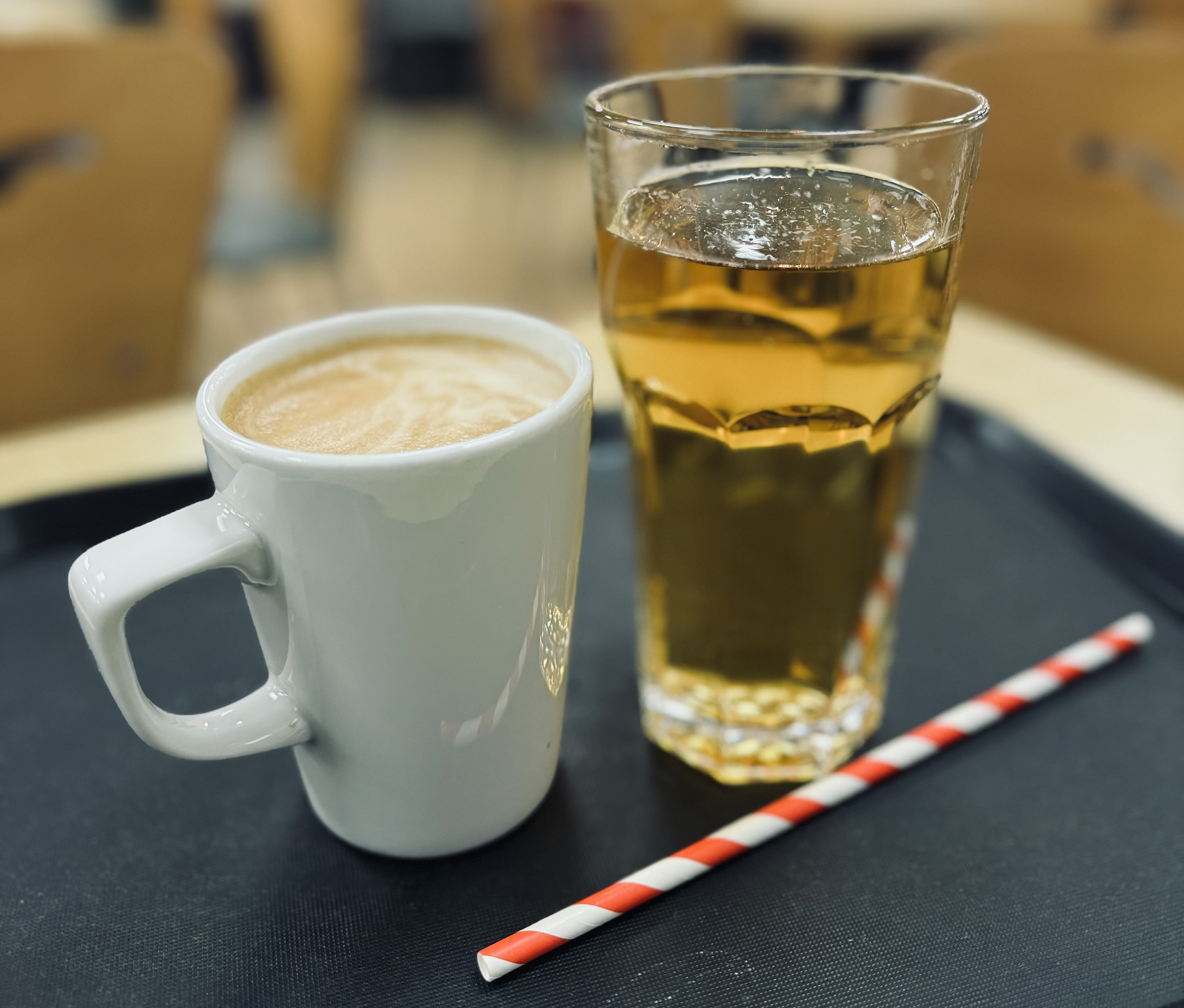 Coffee and a glass of apple juice with a striped straw.