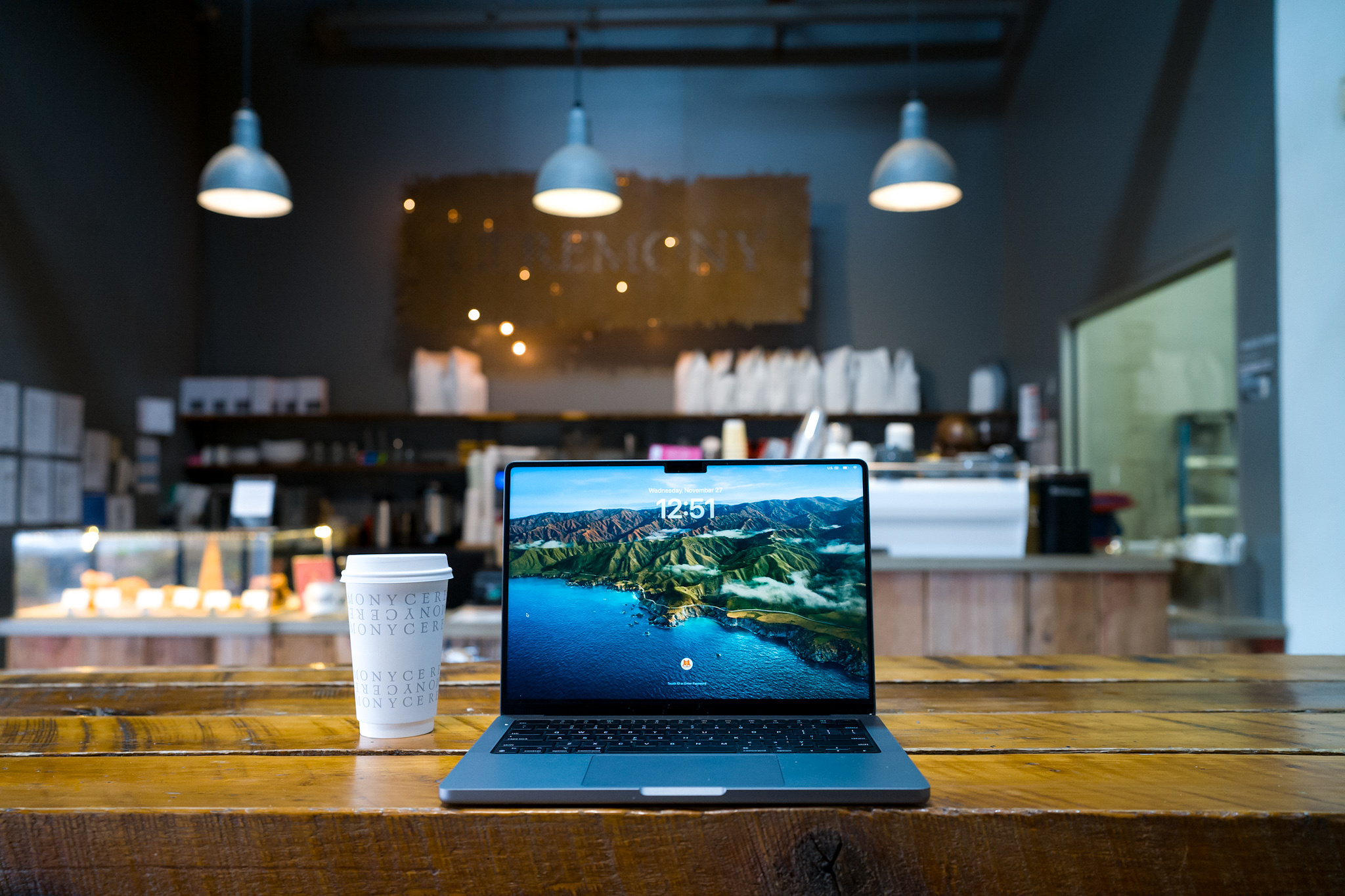 A laptop and cup of coffee on a bar