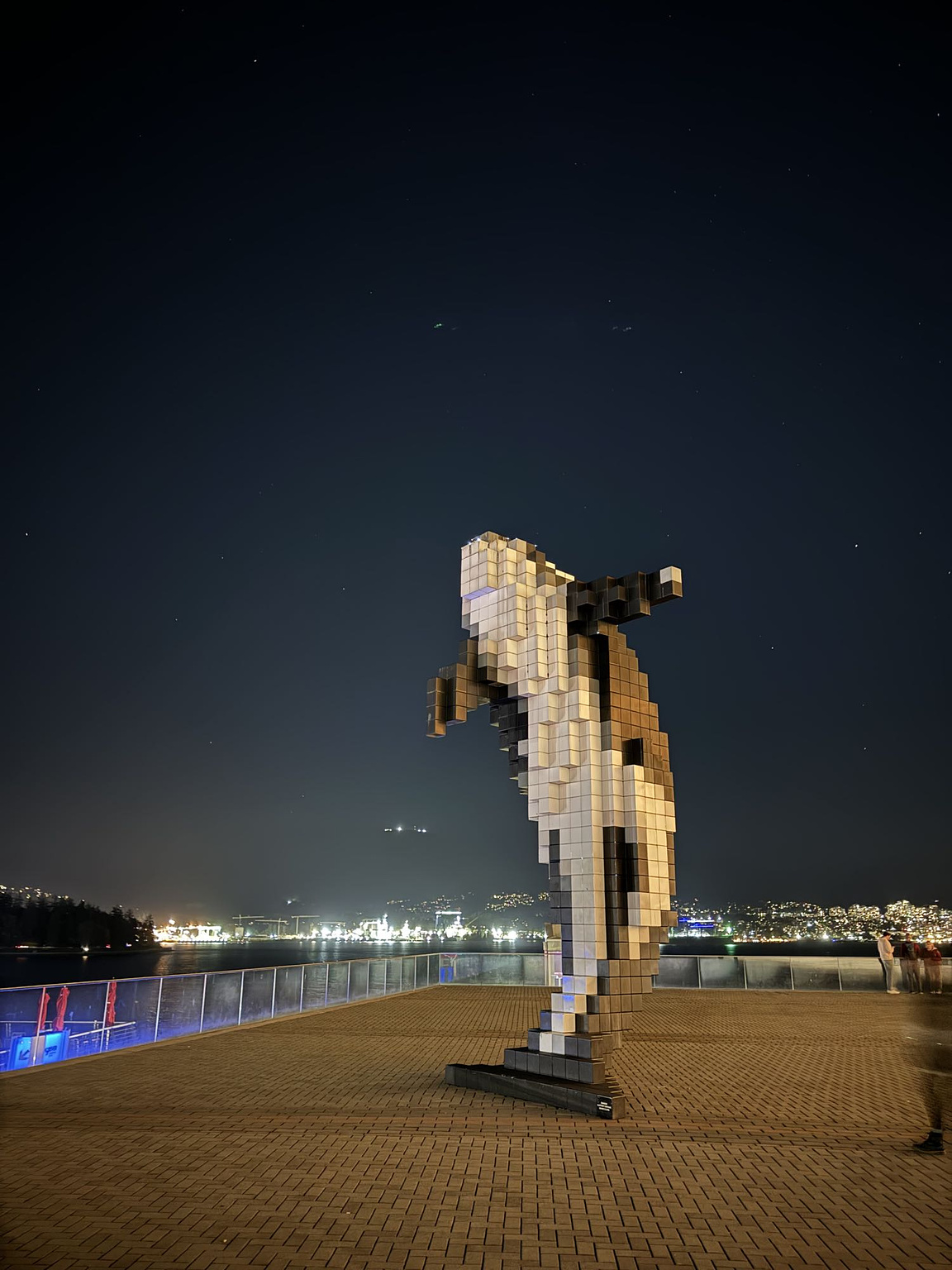 The Digital Orca statue in Vancouver, seen from a low and wide angle with a sky full of stars in the background.