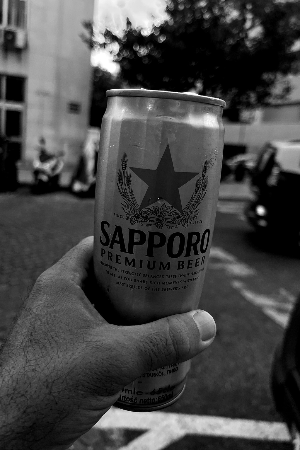 A hand holds a can of Sapporo beer. 