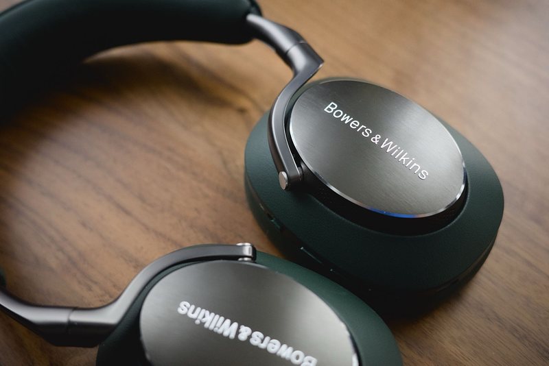 The Px8 on a walnut surface, showcasing their characteristic vivid green leather and brushed metal frame.