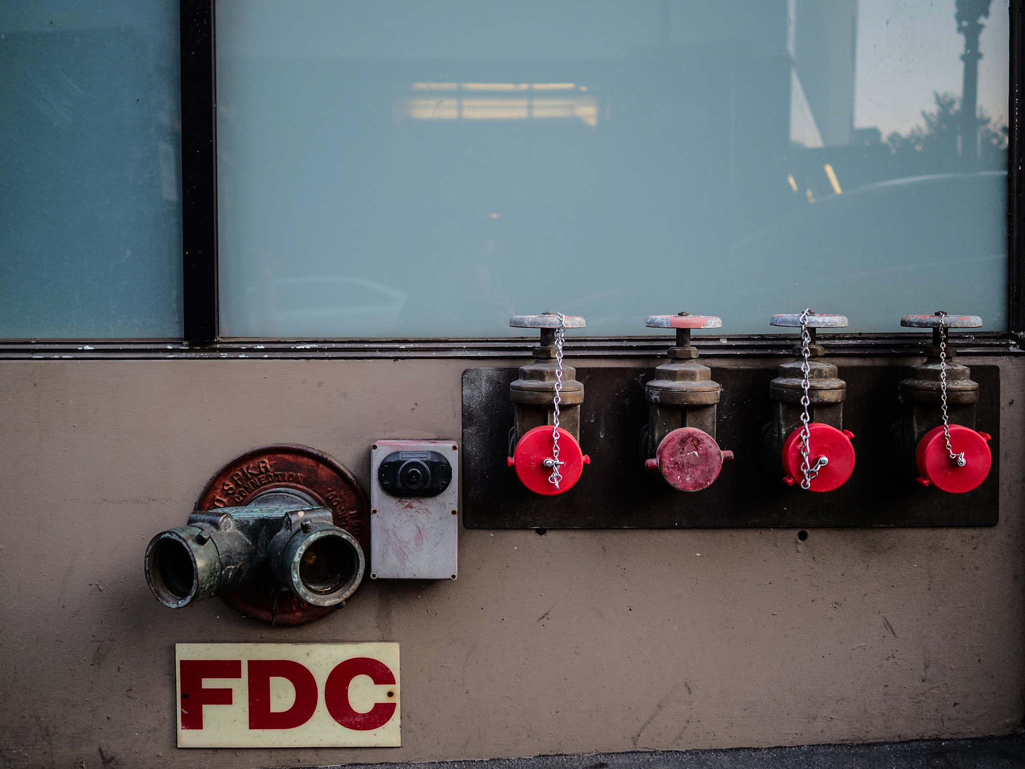 Red-capped fire hose attachments in the side of a building. 