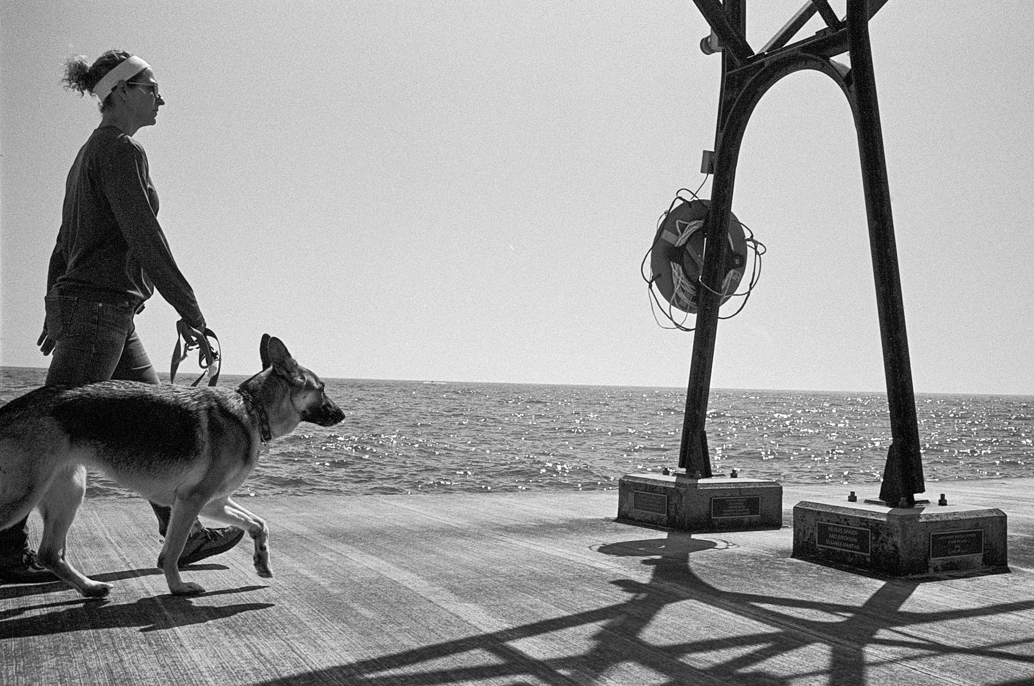 Woman and German Shepherd walking on pier