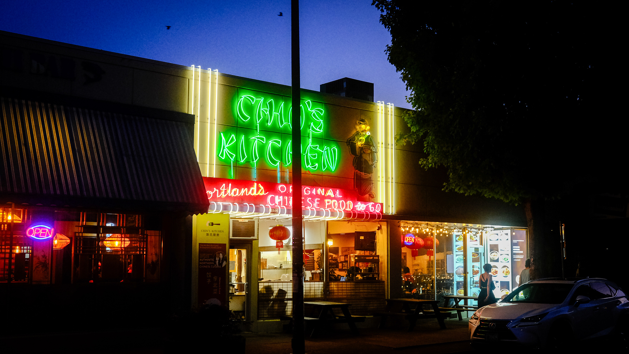 A Chinese restaurant at night with a green and pink neon sign.