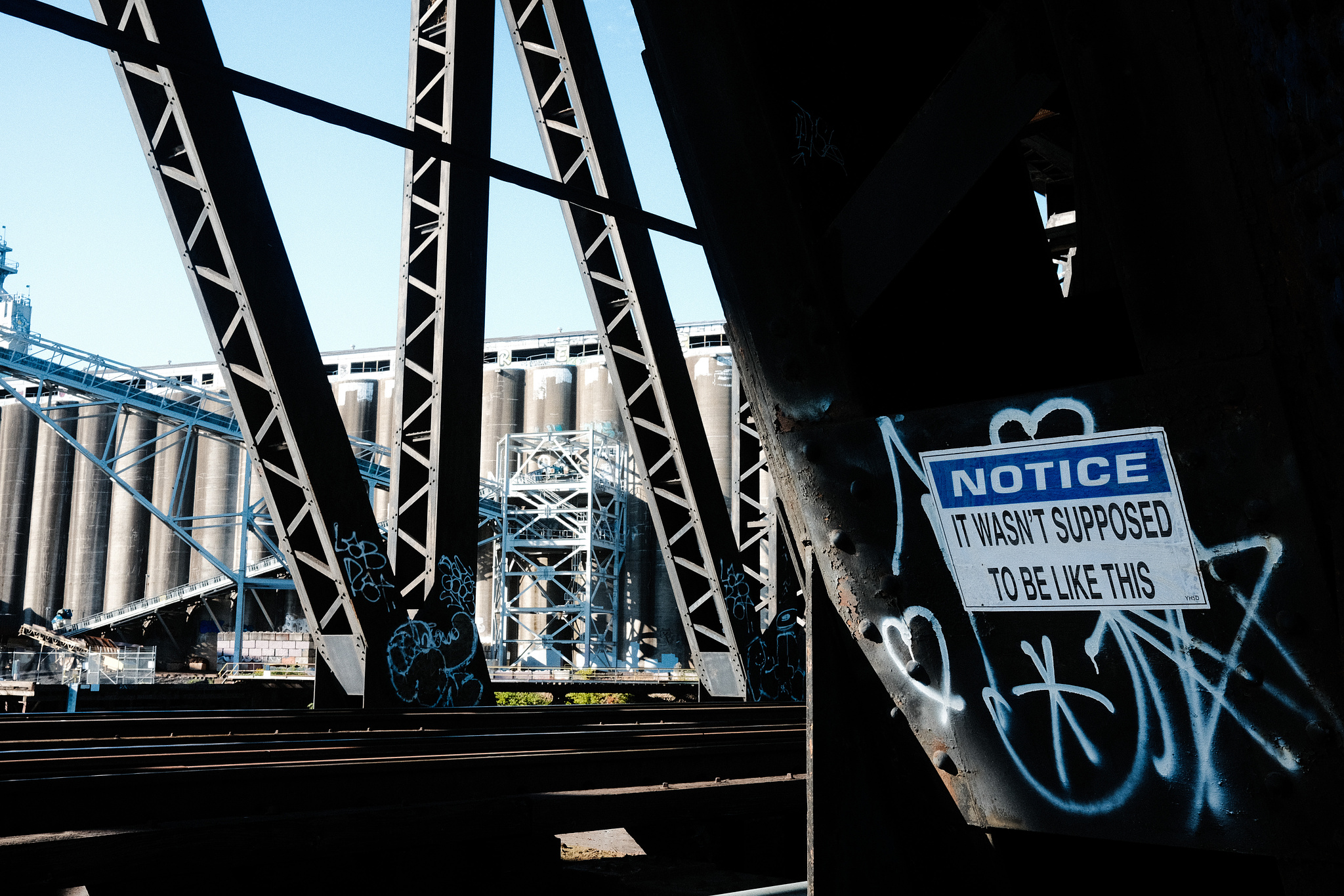 A sign wheatpasted to a steel girder that reads "NOTICE: It wasn't supposed to be like this." 