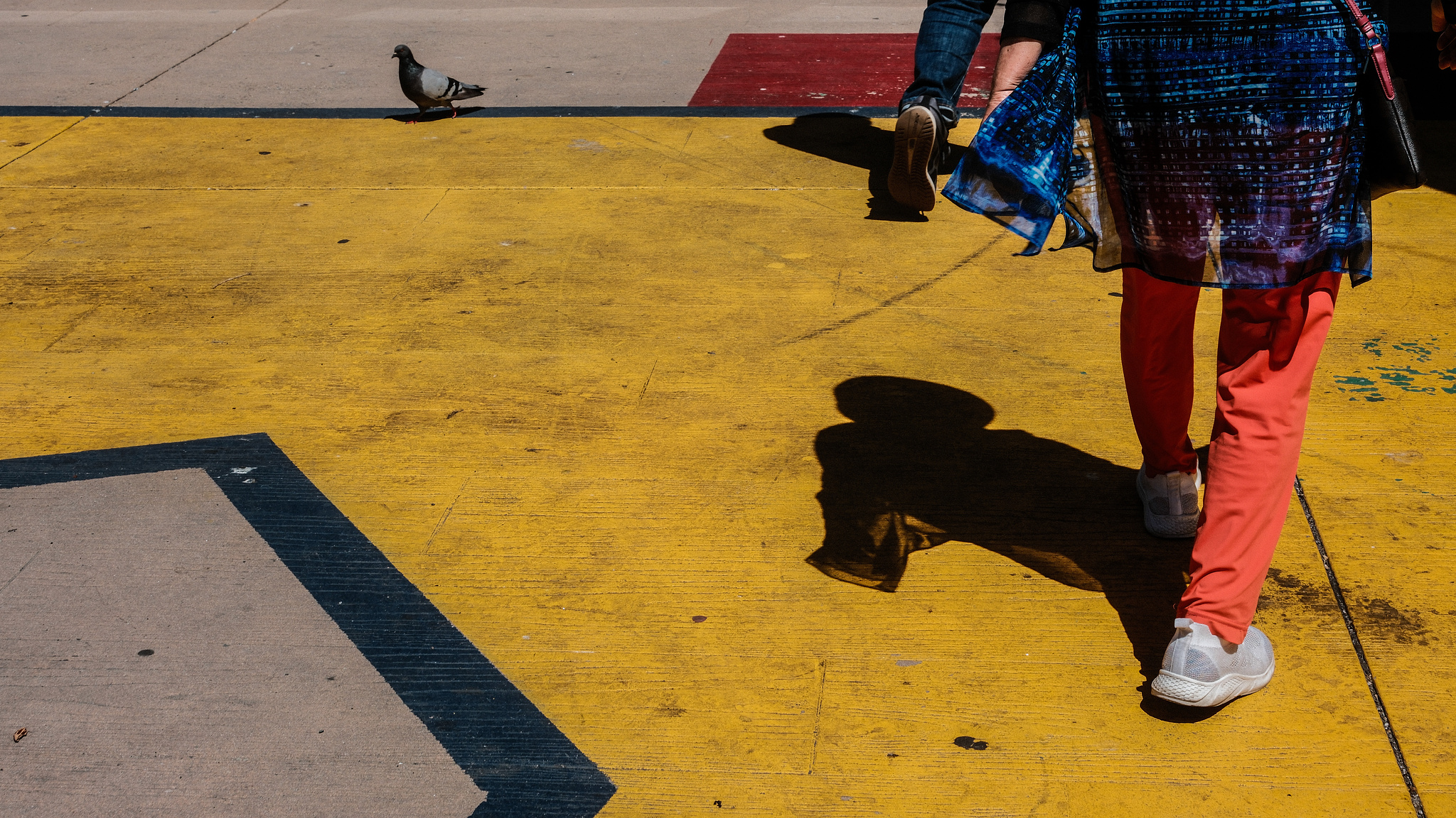 Bright orange pants in the middle of yellow-painted sidewalk