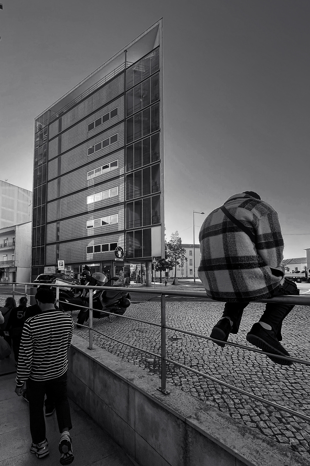 An ugly building, with a person sitting in the foreground.  