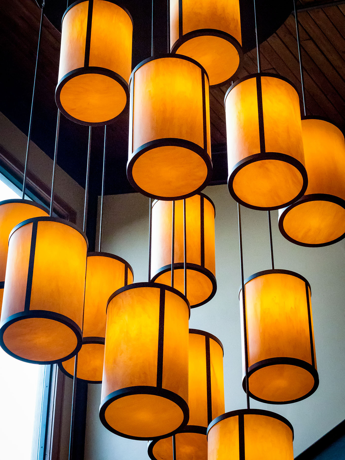 Group of large, cylindrical lights hanging from ceiling.