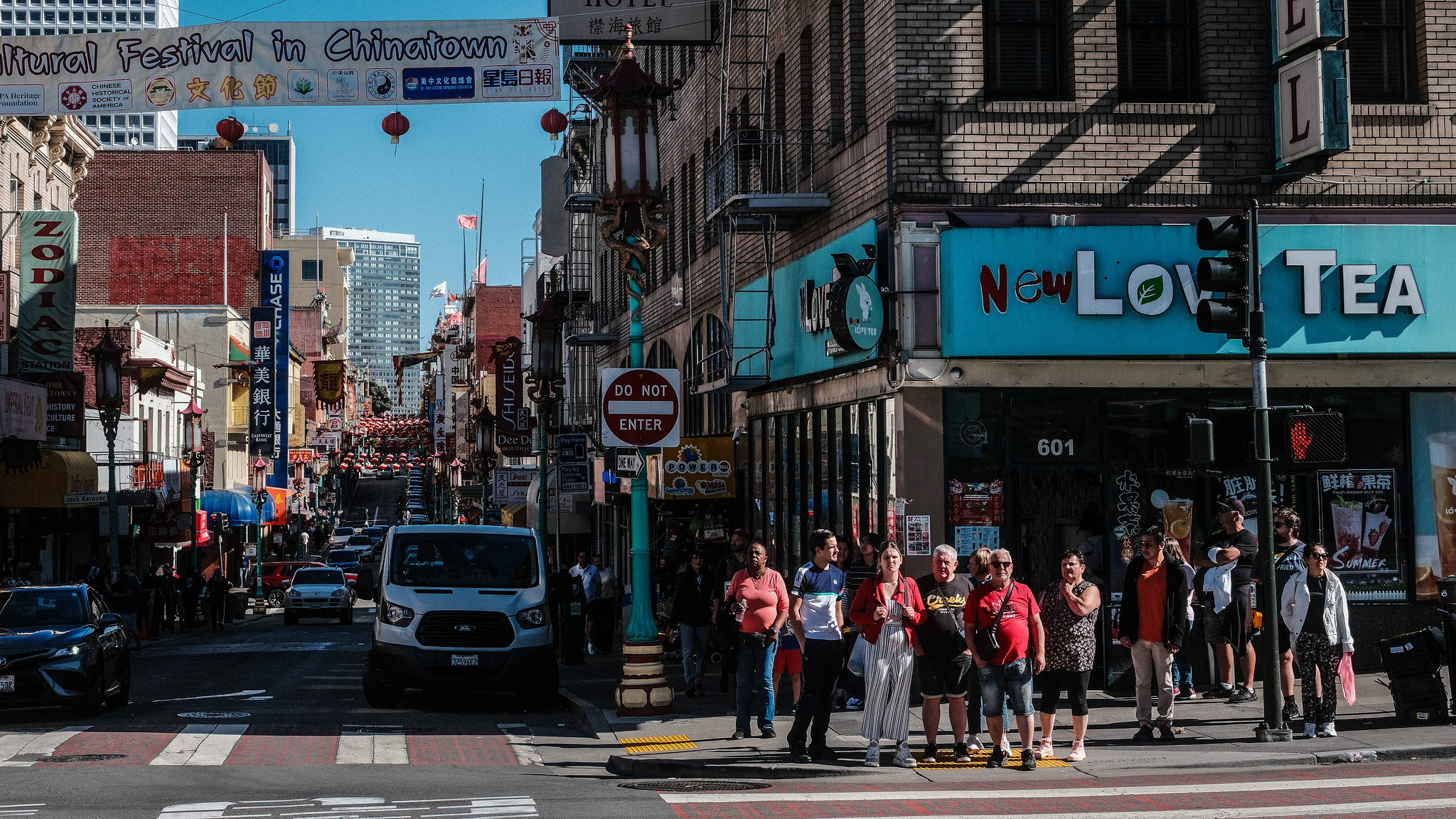 A crowd waits to cross a busy street in Chinatown