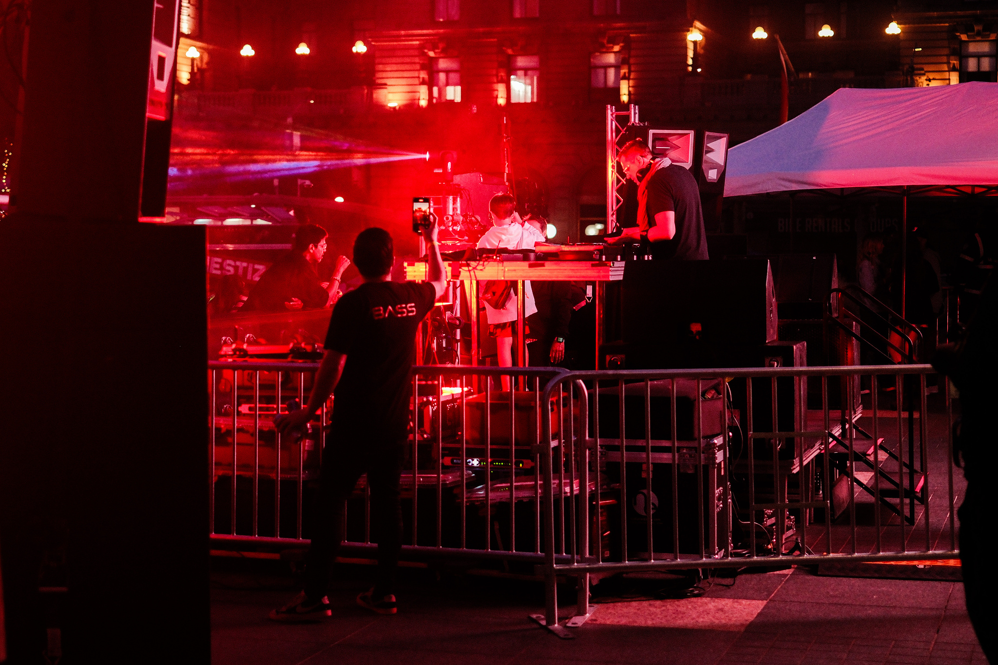 A backstage security guy makes a video of a dj all lit in red