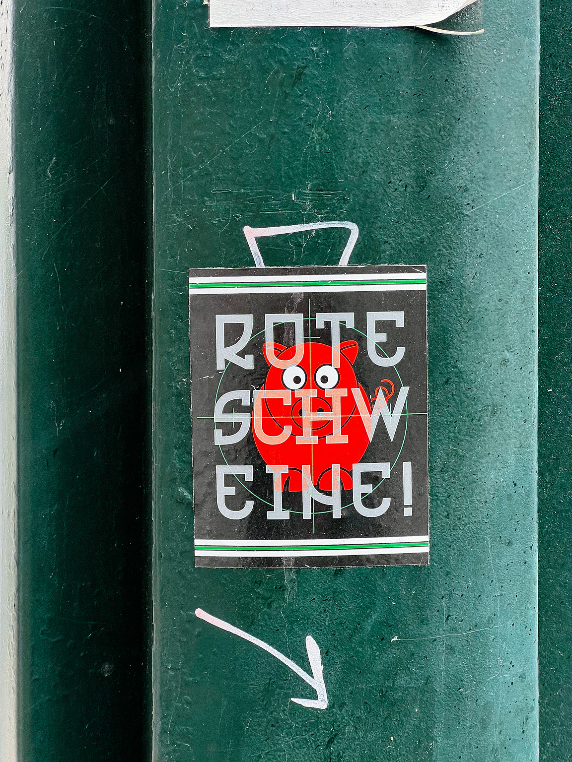 A sticker on a green surface reads "ROTE SCHWEINE!" in bold block letters, with a cartoonish pig illustration.