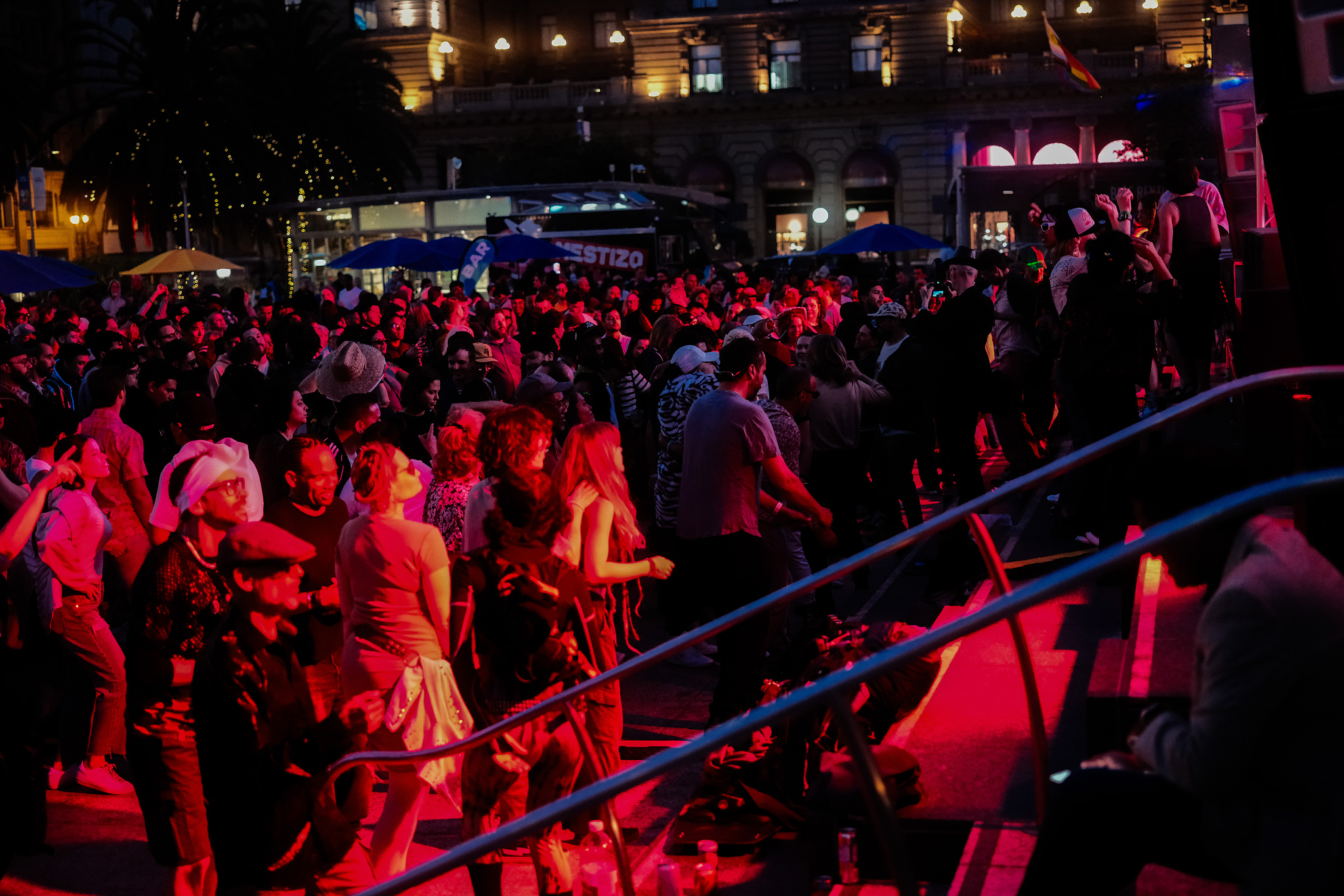 A dancing crowd at an outdoor music event all lit in red