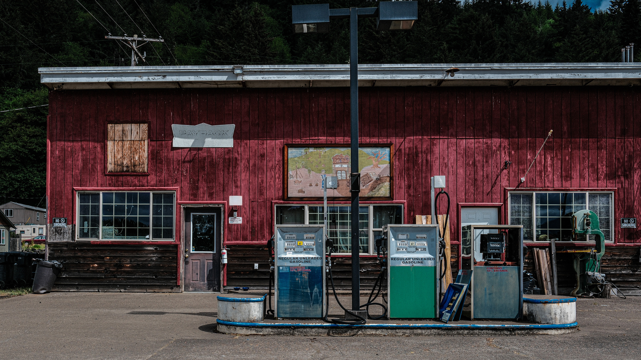 A red gas station with old pumps painted green and blue in front. 