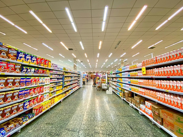 A wide aisle in a well lit grocery store