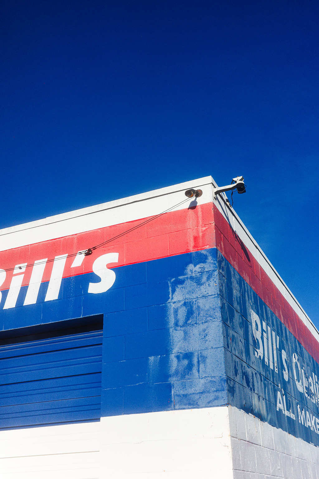 A red, white, and blue-painted building against a brilliant blue sky