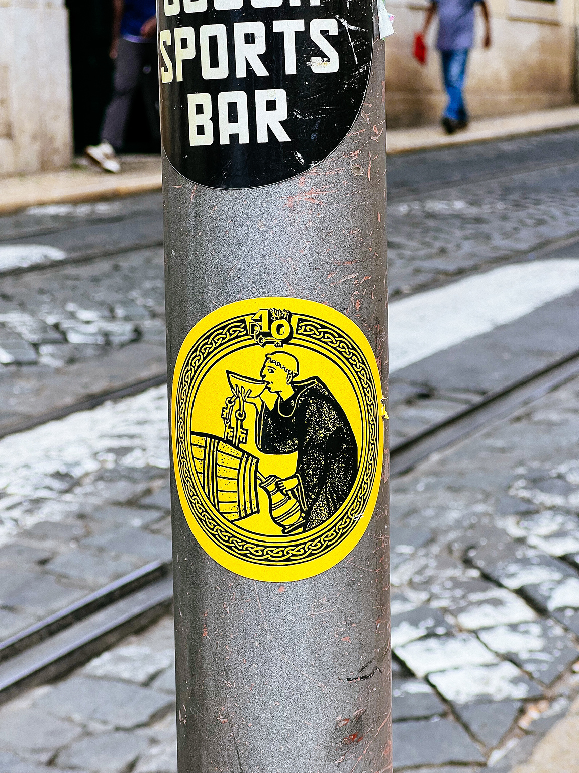 A sticker on a pole depicts a monk drinking wine.