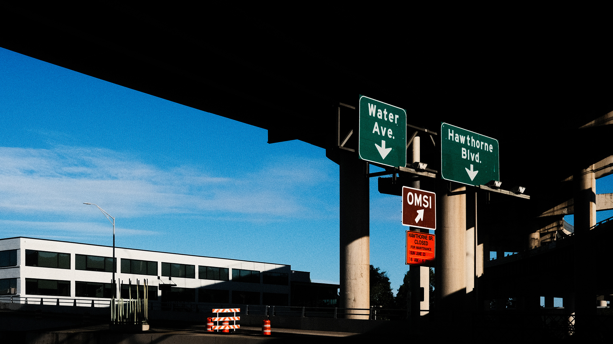 An underpass with signs pointing to Water Ave and Hawthorne Blvd