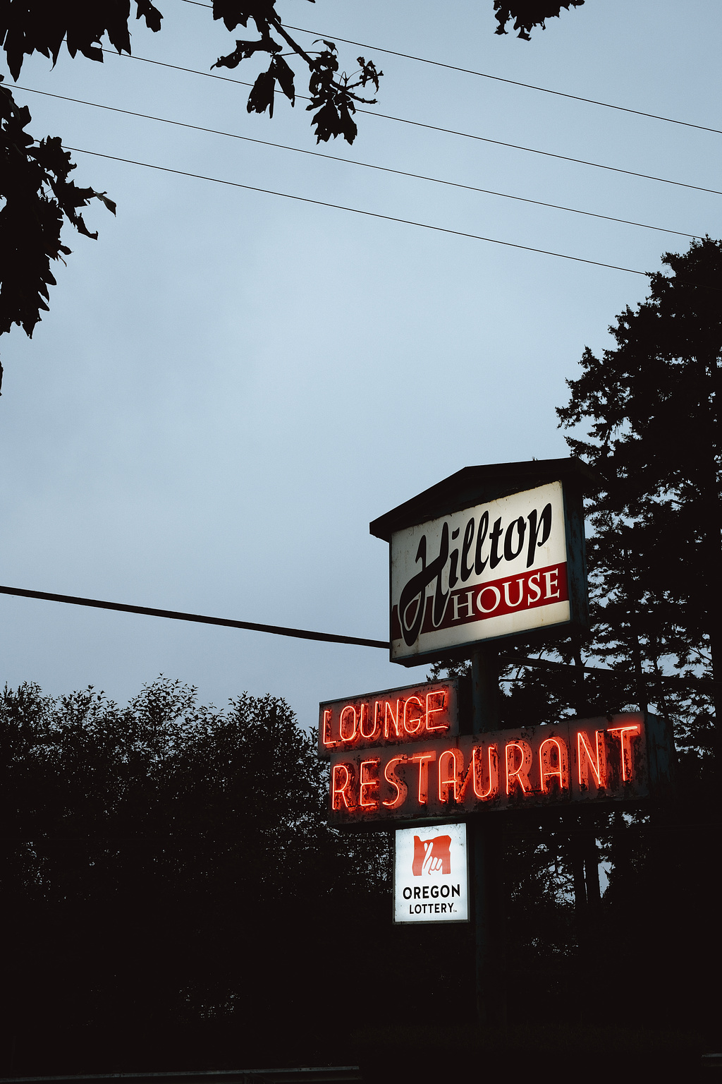 White and red sign that reads "Hilltop House" with "Lounge and Restaurant" in red neon beneath.