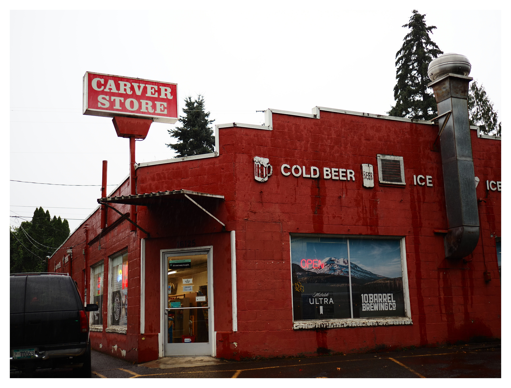 A red brick building with a red sign: "Carver Store." White lettering on the side says "Cold Beer" and "Ice." 