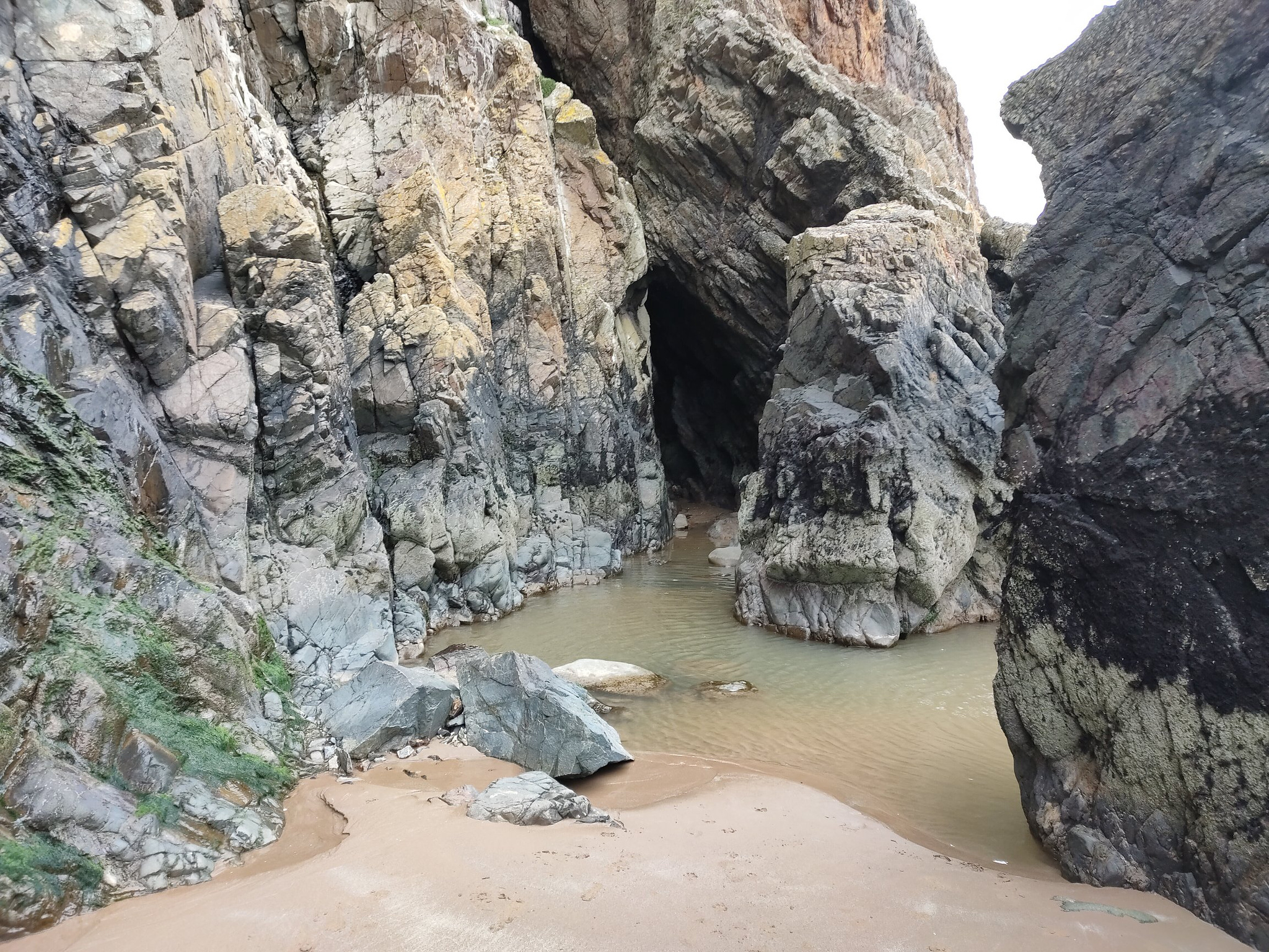 A dramatic rock cliff face, with pools of water