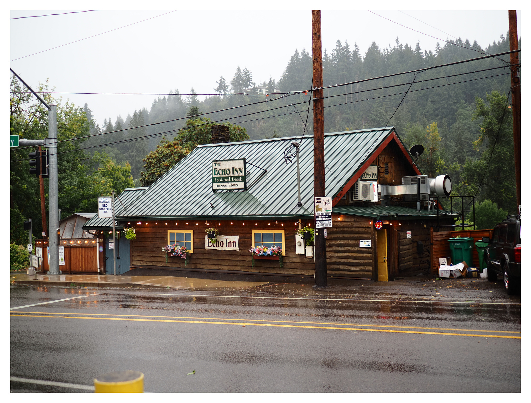 A wooden building with a green metal roof and a white sign with green lettering that reads The Echo Inn