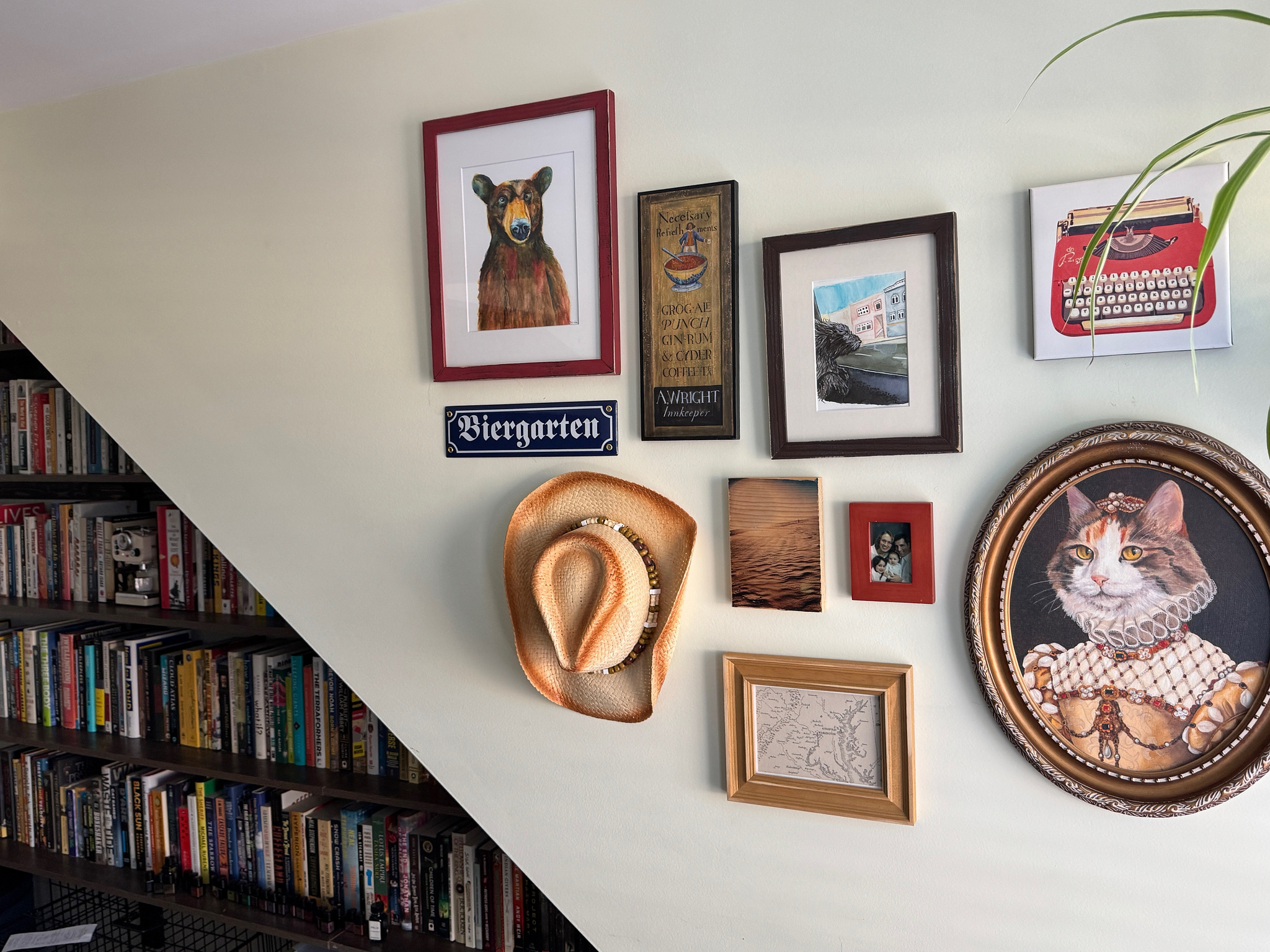 walk with various photos, art, a sign that reads "biergarten", and a cowboy hat. Further along the wall are bookshelves full of books