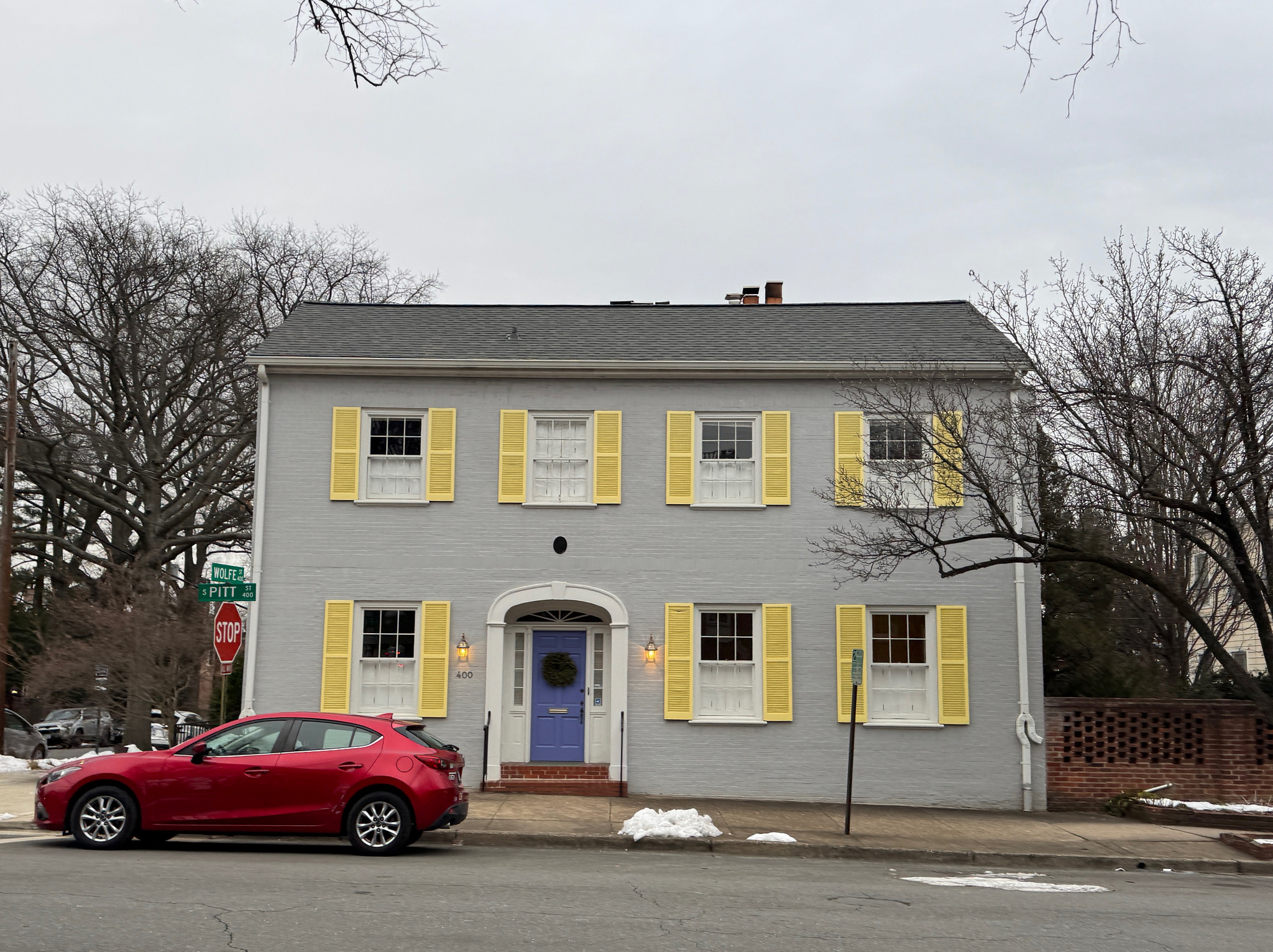 gray, two story home with yellow shutters and a purple door