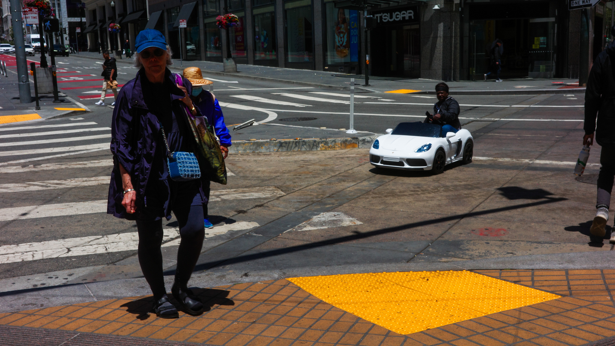 A man in a tiny electric car heads off of the street and on to the sidewalk in San Francisco