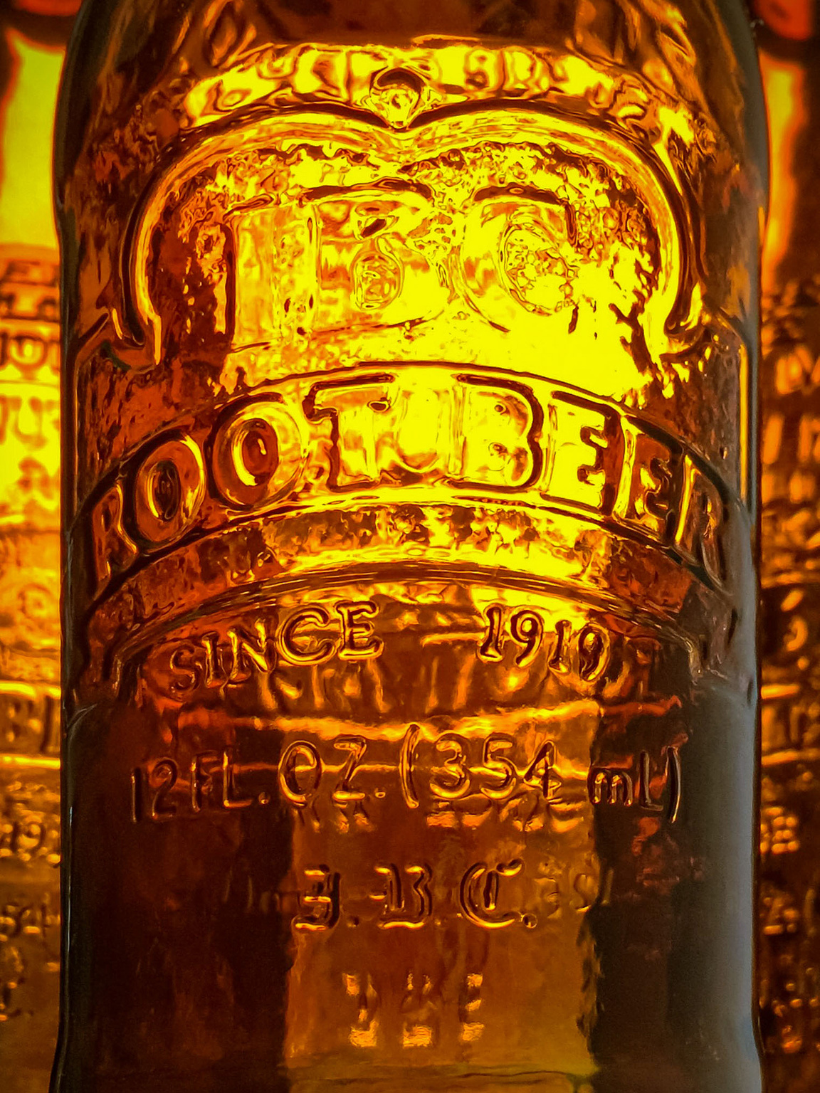 Light glowing through the amber glass of IBC Root Beer bottles.