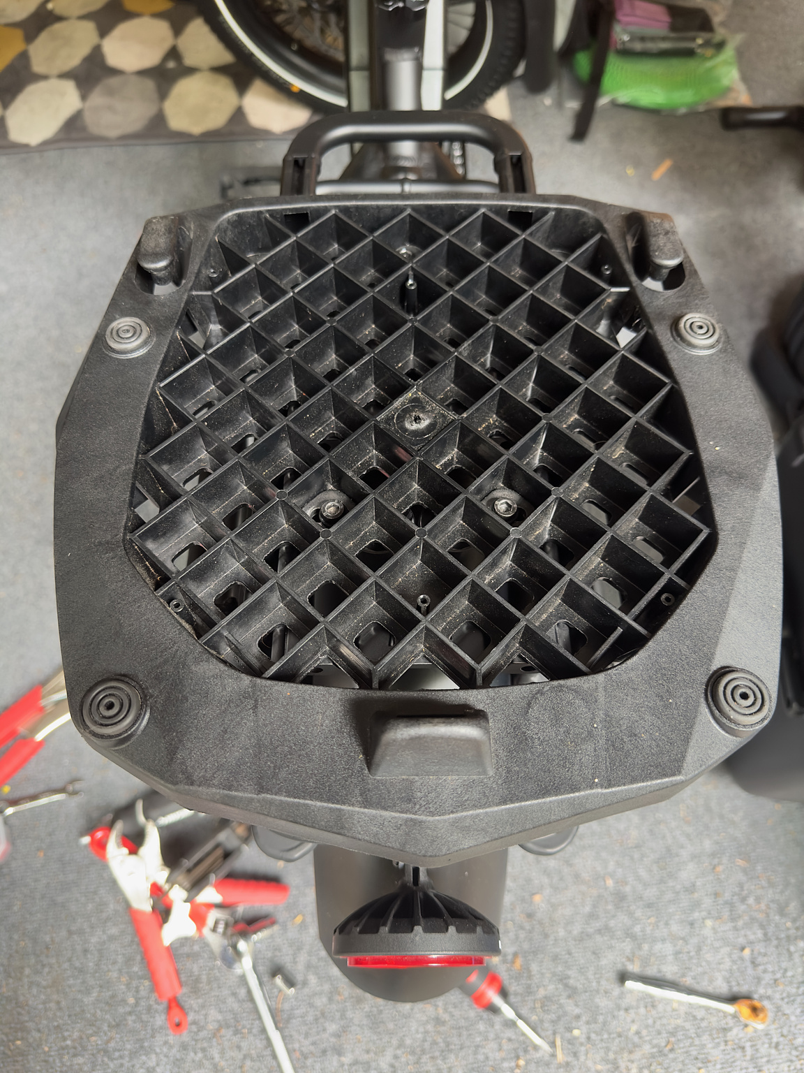 Closeup of a motorcycle topcase mounting plate mounted to the back rack of an ebike. 