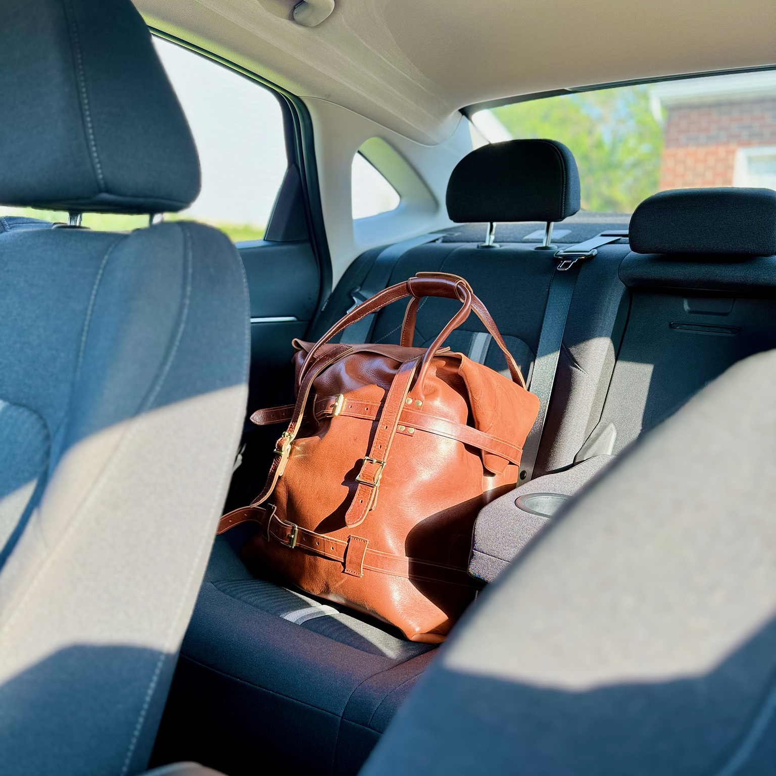 The Strathmere Leather Weekend Bag sitting in the back of my car seat, ready for a trip!