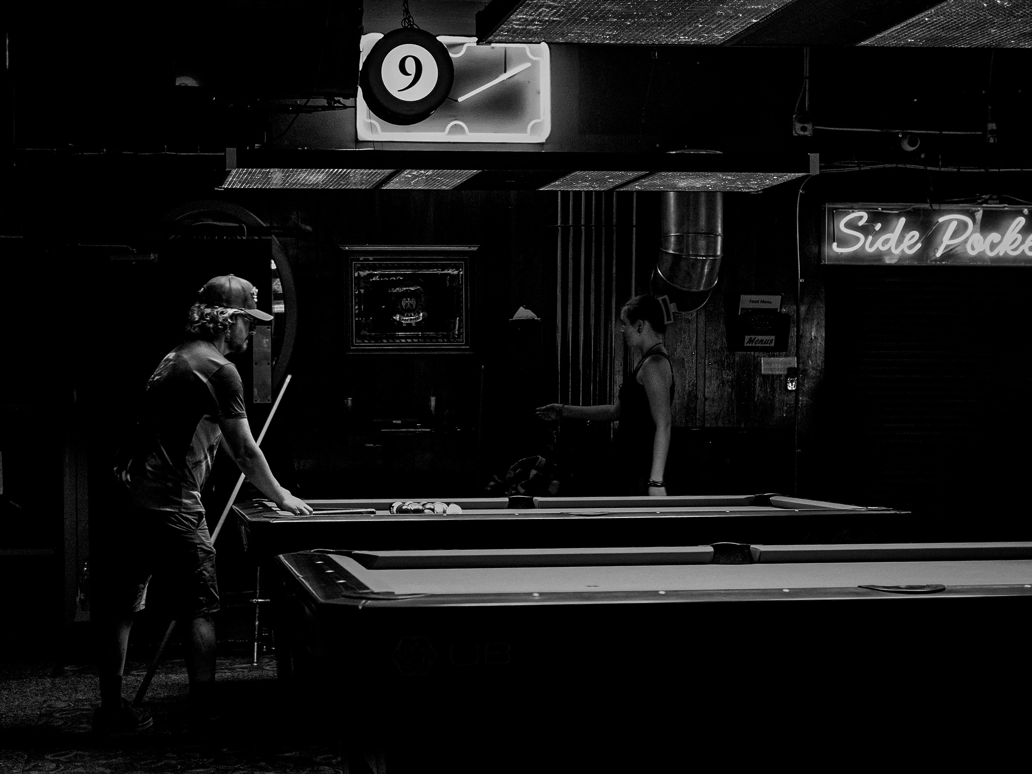 Monochrome. A man considers his shot over a pool table. 