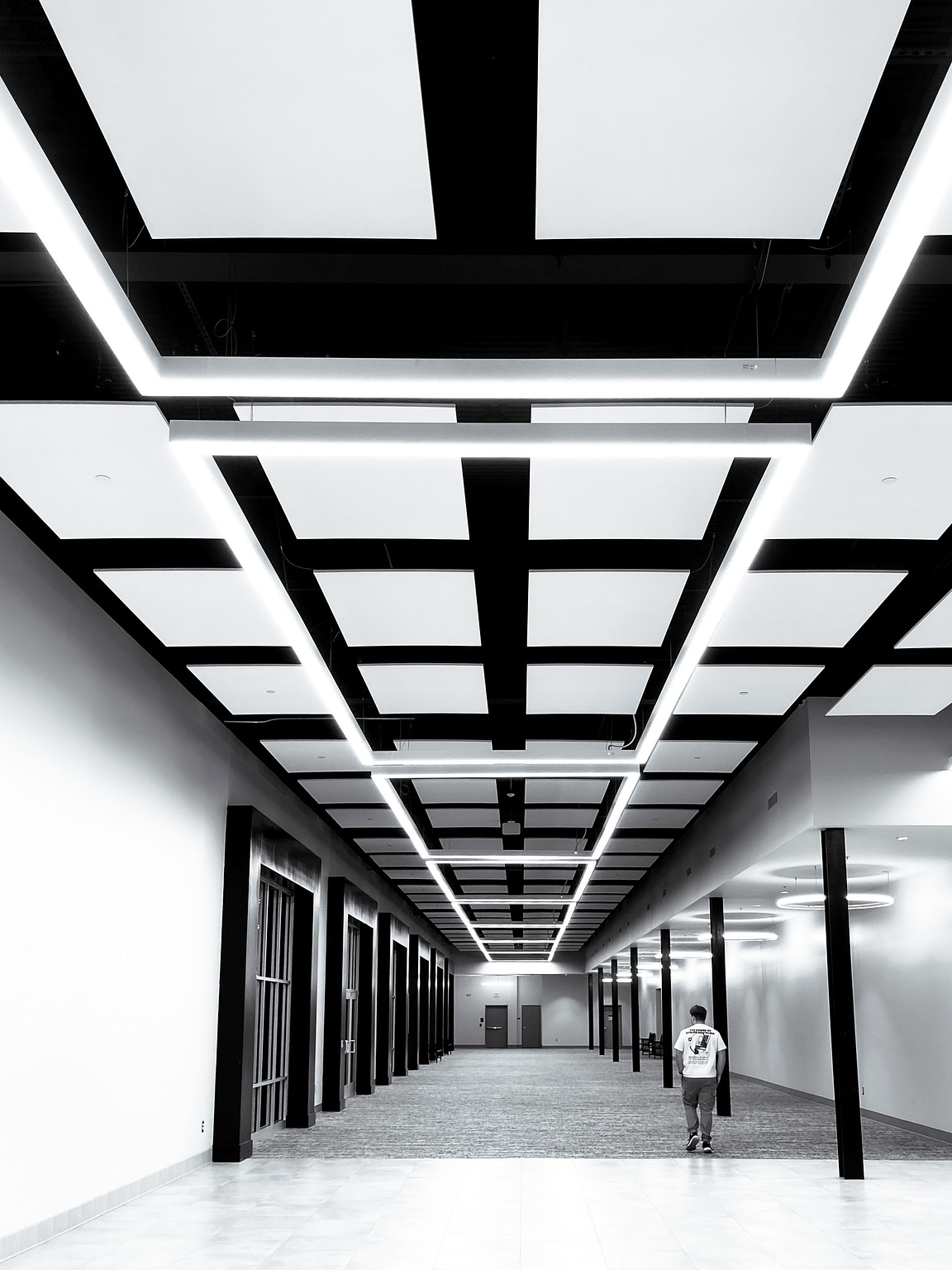 Bright lights illuminate the ceiling of a long hallway.